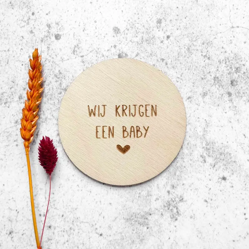 Gegraveerde houten cirkel met de boodschap Wij krijgen een baby